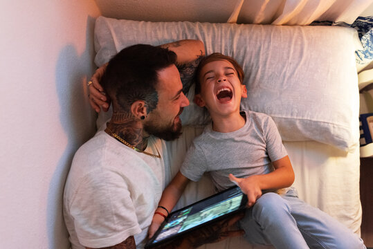 Father and son laughing at video
