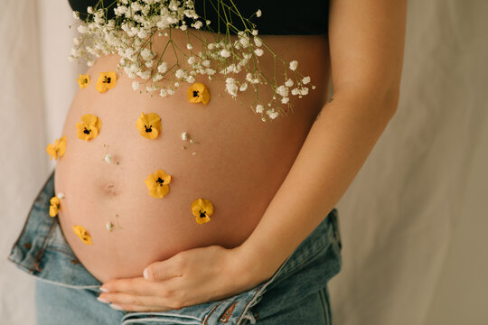 Crop of pregnant woman with flowers
