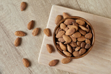 Tasty almond nuts in a bowl on a wooden table, top view. Space for text