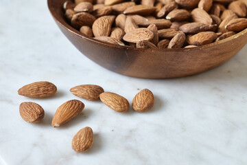 Tasty almond nuts in a wooden bowl on a marble table, side view. Space for text