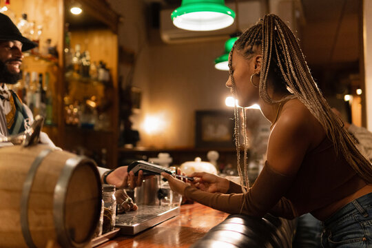 Black female paying for drink in bar