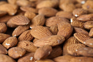 Tasty almond nuts on a wooden plate on a wooden table, top view. Space for text