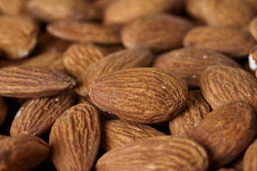 Tasty almond nuts on a wooden plate on a wooden table, top view. Space for text