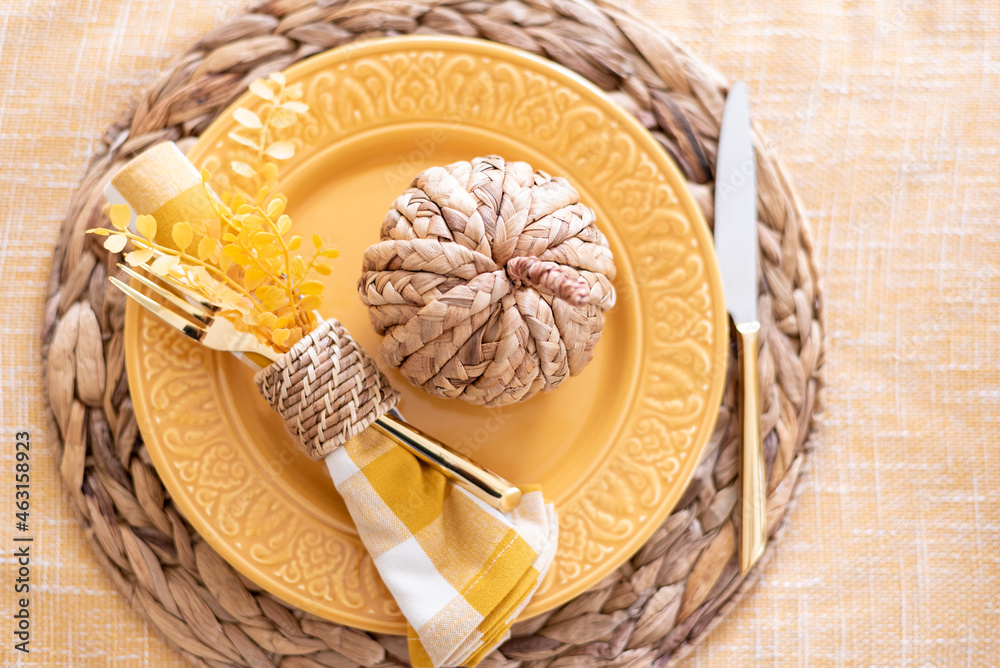 Wall mural Top view of a fall table setting with yellow plate and wicker pumpkin