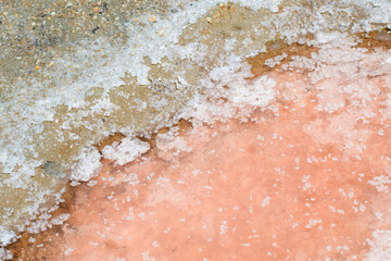 Salt crystals close-up at the bottom of a pink lake. Natural salt mining industry.