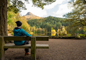 Landscape photography of lake, mountains, forest, autumn, bench, woman, Glencoe Lochan, Scotland
