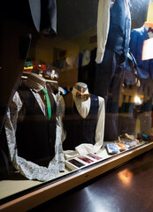 Business modern suit with bow tie on a mannequin through a glass kept as display in a cloth shop, shopping for men concept