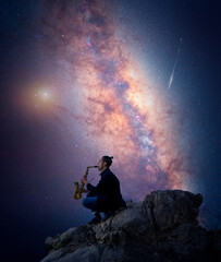 Fototapeta premium latin musician is playing saxophone on the top of the mountain with Milky Way background 