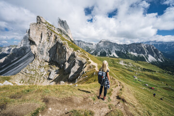 Fototapeta na wymiar Women hiker on hiking trail path and epic landscape of Seceda peak in Dolomites Alps, Odle mountain range, South Tyrol, Italy, Europe