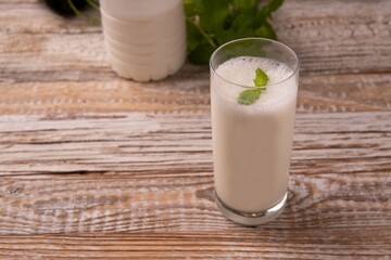 Turkish or Azerbaijan traditional Drink Ayran or Kefir with herbs and with mint in a glass on a wooden table front view. Fermented milk drink for diet. Copy space. the concept of healthy nutrition.