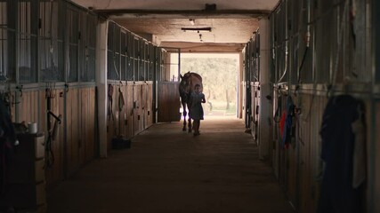 Girl leading horse in stable