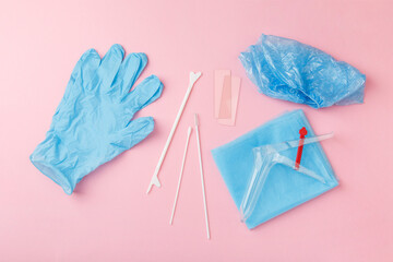 preventive gynecological examination. Prevention for womens health. Basic set for vaginal examination on pink background. Gynecological speculum,  gloves, diaper and shoe covers. Female health concept