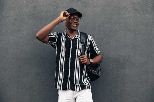 portrait of an African American man against a black wall, looking to the side, smiling broadly, wearing shirt and shert