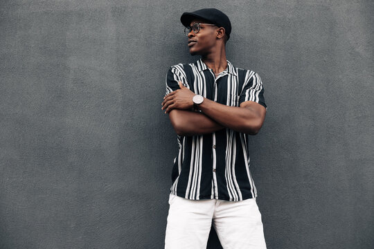 portrait of an African American man against a black wall, looking to the side, smiling broadly, wearing shirt and shert