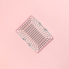 Empty market basket isolated on pastel pink background. Minimal flat lay. Shortage or scarcity or consumerism concept.