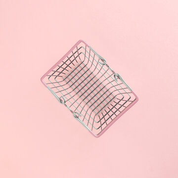 Empty market basket isolated on pastel pink background. Minimal flat lay. Shortage or scarcity or consumerism concept.