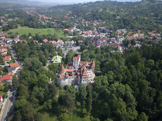 Obraz premium Aerial view of Bran Village and Bran castle in Transylvania, Romania with white houses, red roofs, green trees and blue sky