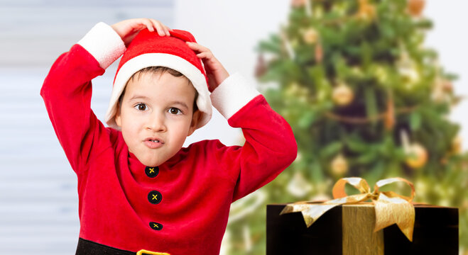 Child wearing Santa hats and stressed at Christmas. Funny image of Caucasian male model with a tree at home