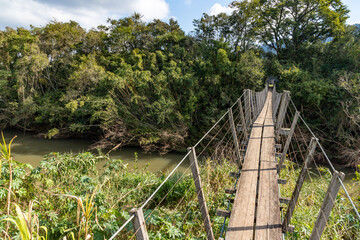 Fototapeta premium Wood and iron bridge over Cadeia river with forest around