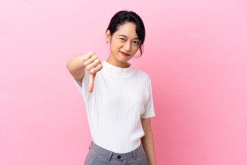Young Vietnamese woman isolated on pink background showing thumb down with negative expression