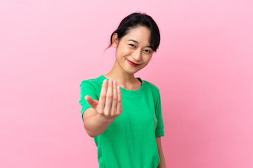 Young Vietnamese woman isolated on pink background inviting to come with hand. Happy that you came