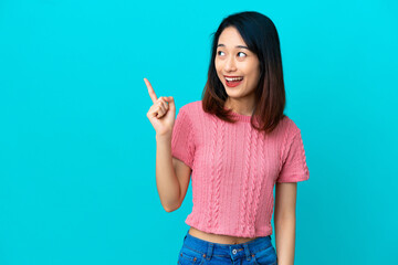 Young Vietnamese woman isolated on blue background intending to realizes the solution while lifting a finger up