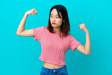 Young Vietnamese woman isolated on blue background doing strong gesture