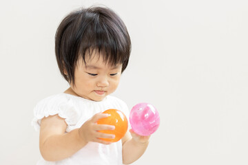 ガチャガチャのカプセルを持つ赤ちゃん（1歳2か月、日本人、女の子）