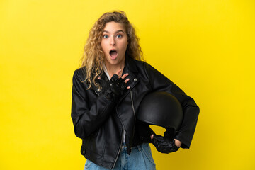 Fototapeta na wymiar Young blonde woman with a motorcycle helmet isolated on yellow background surprised and shocked while looking right