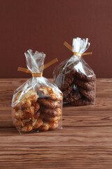 Chocolate oatmeal cookies and shortbread cookies with almond flakes in transparent bags on a wooden table. Closeup