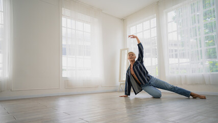 Asian Male ballet dancer of dancing in room with glass windows and white curtain. Exercise at home with new normal lifestyle.