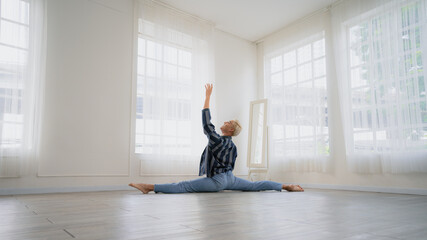 Asian Male ballet dancer of dancing in room with glass windows and white curtain. Exercise at home with new normal lifestyle.