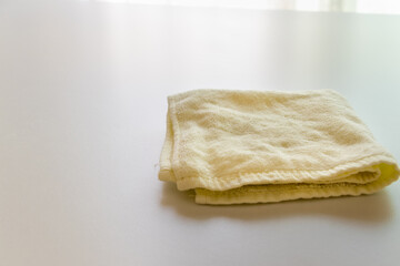 テーブルの上にたたんで置かれた淡い黄色のタオル