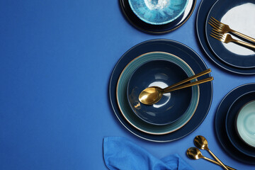 Clean dishware and cutlery on blue background, flat lay. Space for text