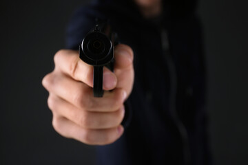 Man aiming gun on dark background, closeup