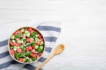 Delicious salad with watermelon, cucumber, arugula and feta cheese on white wooden table, flat lay. Space for text
