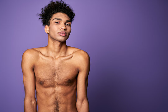 Portrait of latin american transgender model on purple background. Handsome young man posing camera