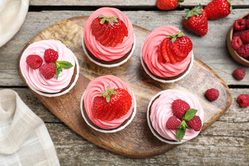 Sweet cupcakes with fresh berries on wooden table, flat lay