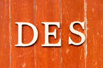 Alphabet letter in word DES (Abbreviation of Delivered Ex Ship) on old red color wood plate background