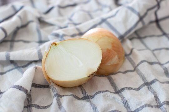 Fresh Cut Yellow Onion On A White Plaid Towel In The Kitchen