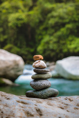 Rocks stacked in balance in a peaceful rainforest on the side of a river in a national park of Costa Rica