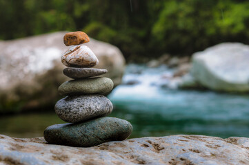 Rocks stacked in balance in a peaceful rainforest on the side of a river in a national park of...
