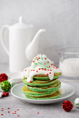 Green pancakes served with white glaze and whipped cream