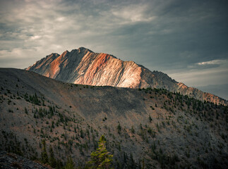 Mountain range part of which is illuminated by the sun under a dramatic sky