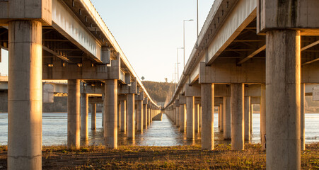Obraz premium Highway bridge crossing a river during the sunset taken from the front side 