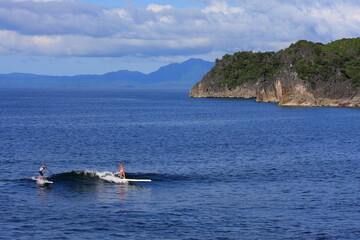 girl surfing an SUP standup paddle board in tropical blue ocean. 