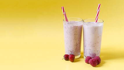 Milkshakes in transparent dishes with raspberries and strawberries on a bright background side view of kopi space. Cocktails of ice cream, milk and berries on a colored background