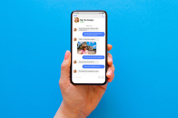 Woman using messaging app on her phone, mockup of sample chat application interface on blue...