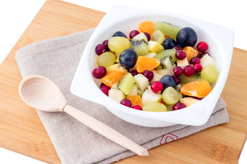 Fruit fresh healthy salad in a white bowl of kiwi, apple, tangerine, grapes and cranberries for a healthy diet. 
