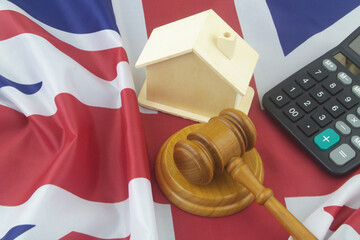 Real estate and legal questions in UK. Wooden gavel, calculator and house model on British flag.